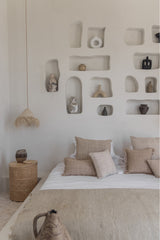the handmade cushion cover bumi satu arrange on a bed with other cushions.