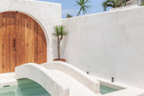 photograph of a minimalistic white pool with bridge