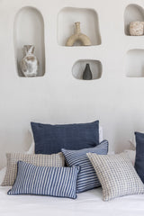 the bespoke cushion cover biru arrange on a bed with other hand made cushion covers from indonesia
